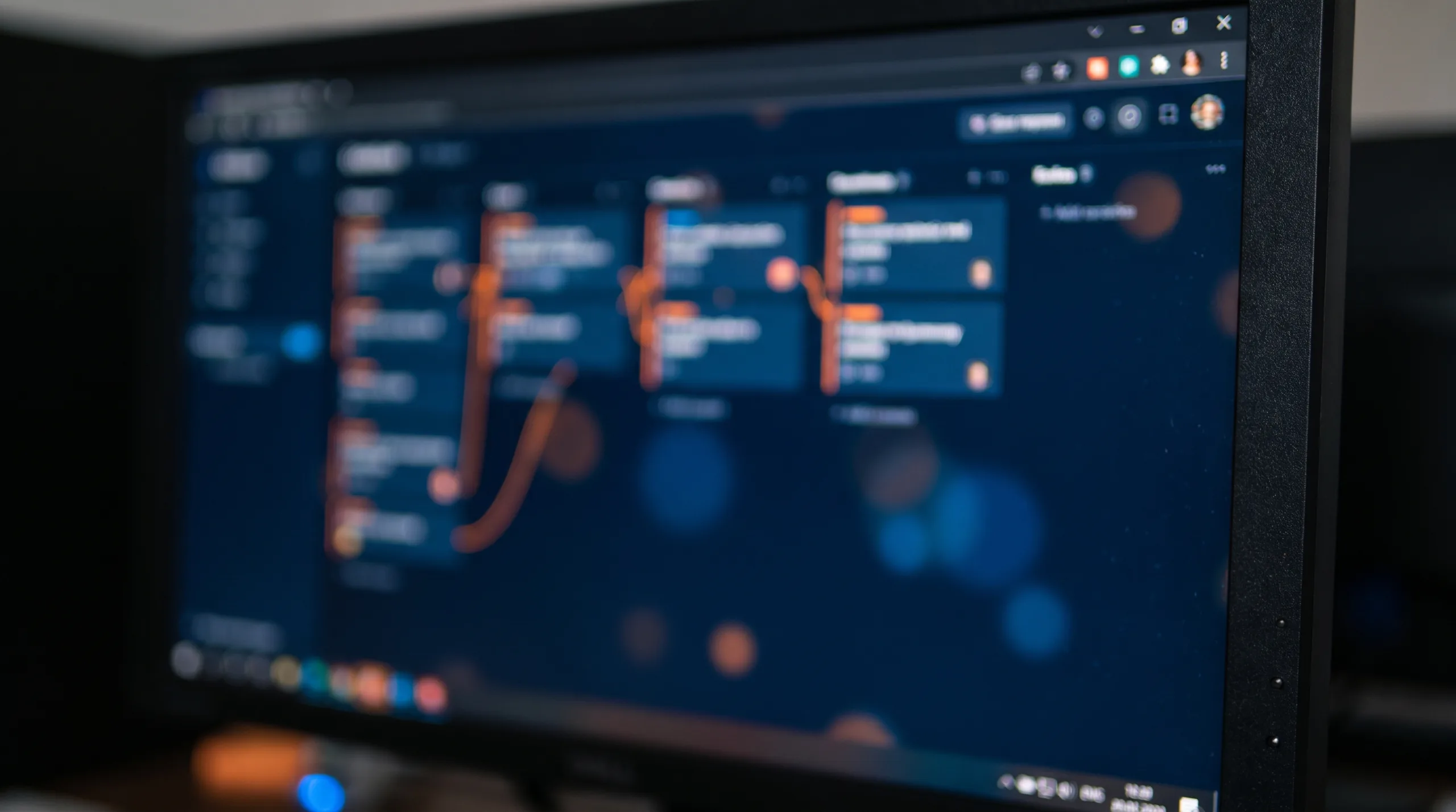 Web application task board in navy and orange on a monitor, softly out of focus